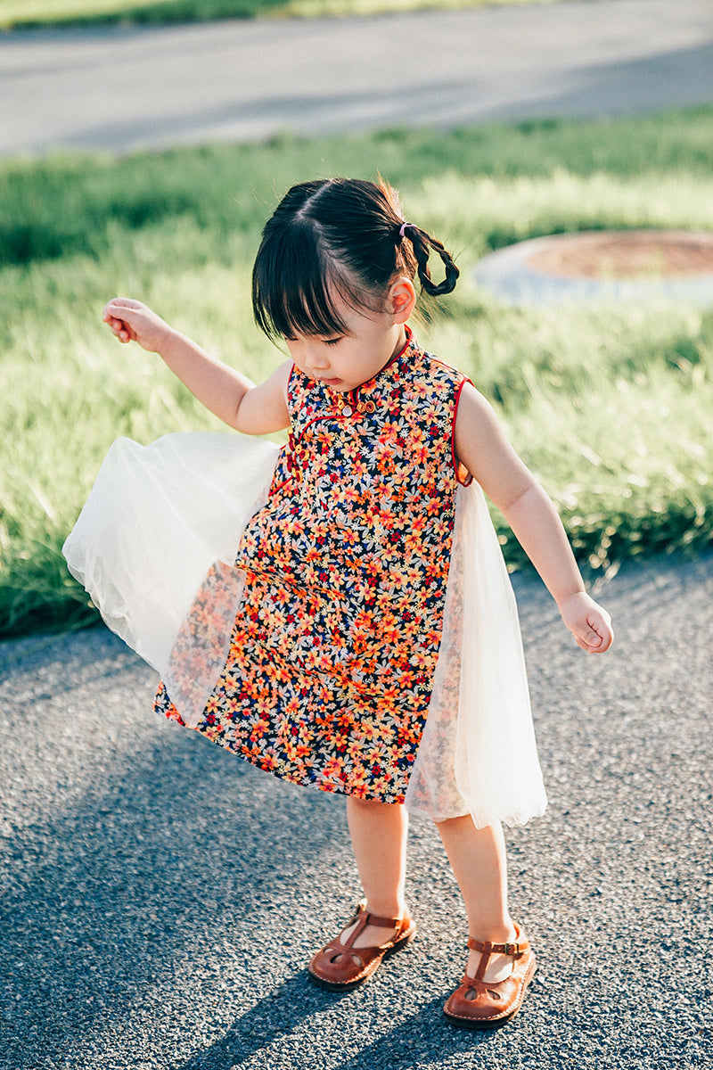 Girl wearing a navy floral qipao-inspired dress with ivory tulle side panels