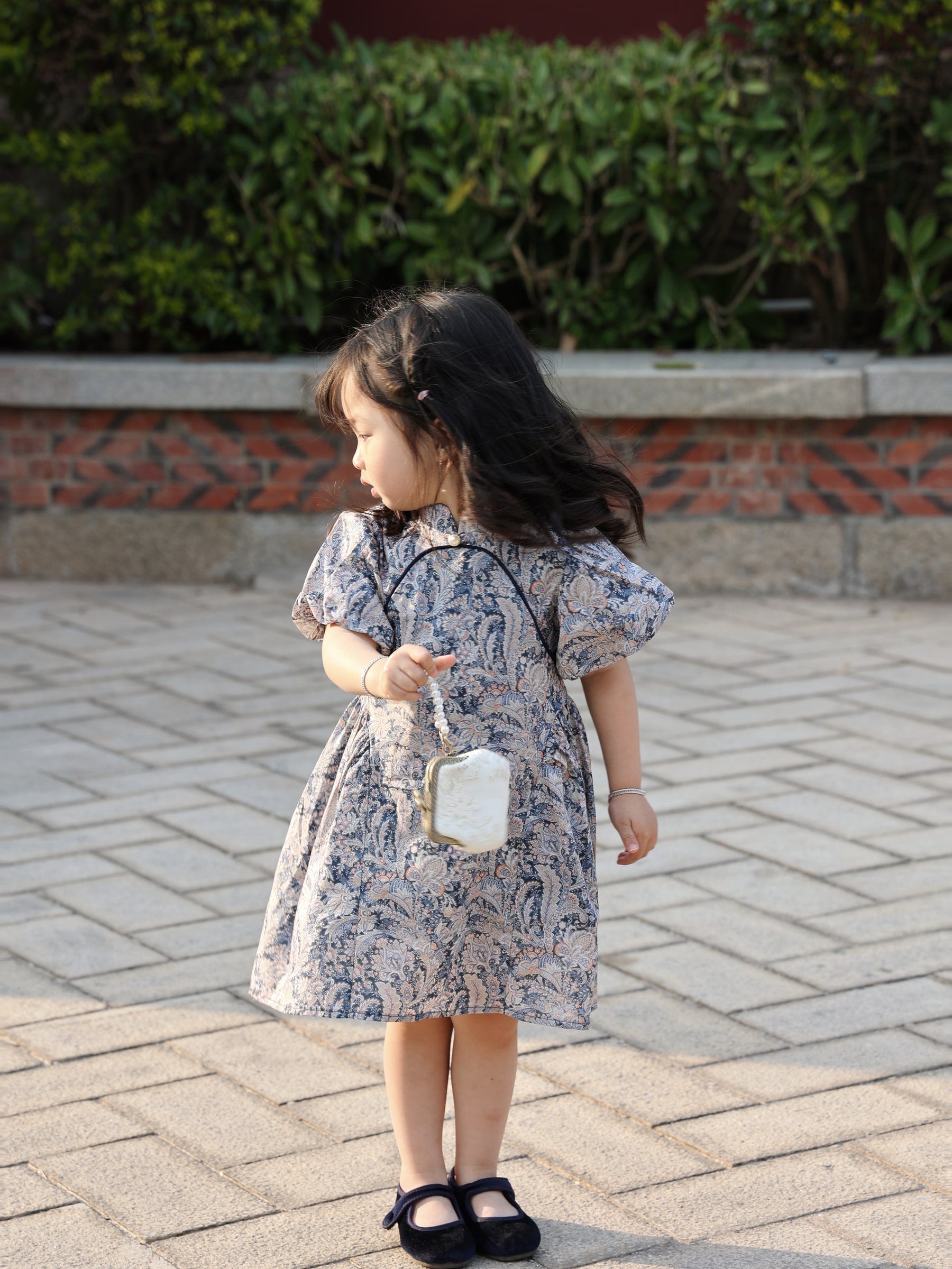 Girl wearing the Blue Paisley puff-sleeve qipao dress in warm light
