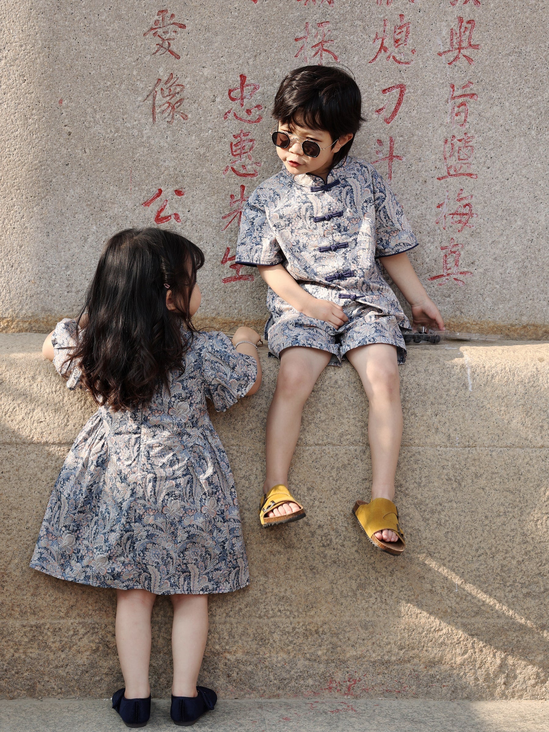 Siblings relaxing in coordinated Blue Paisley outfits