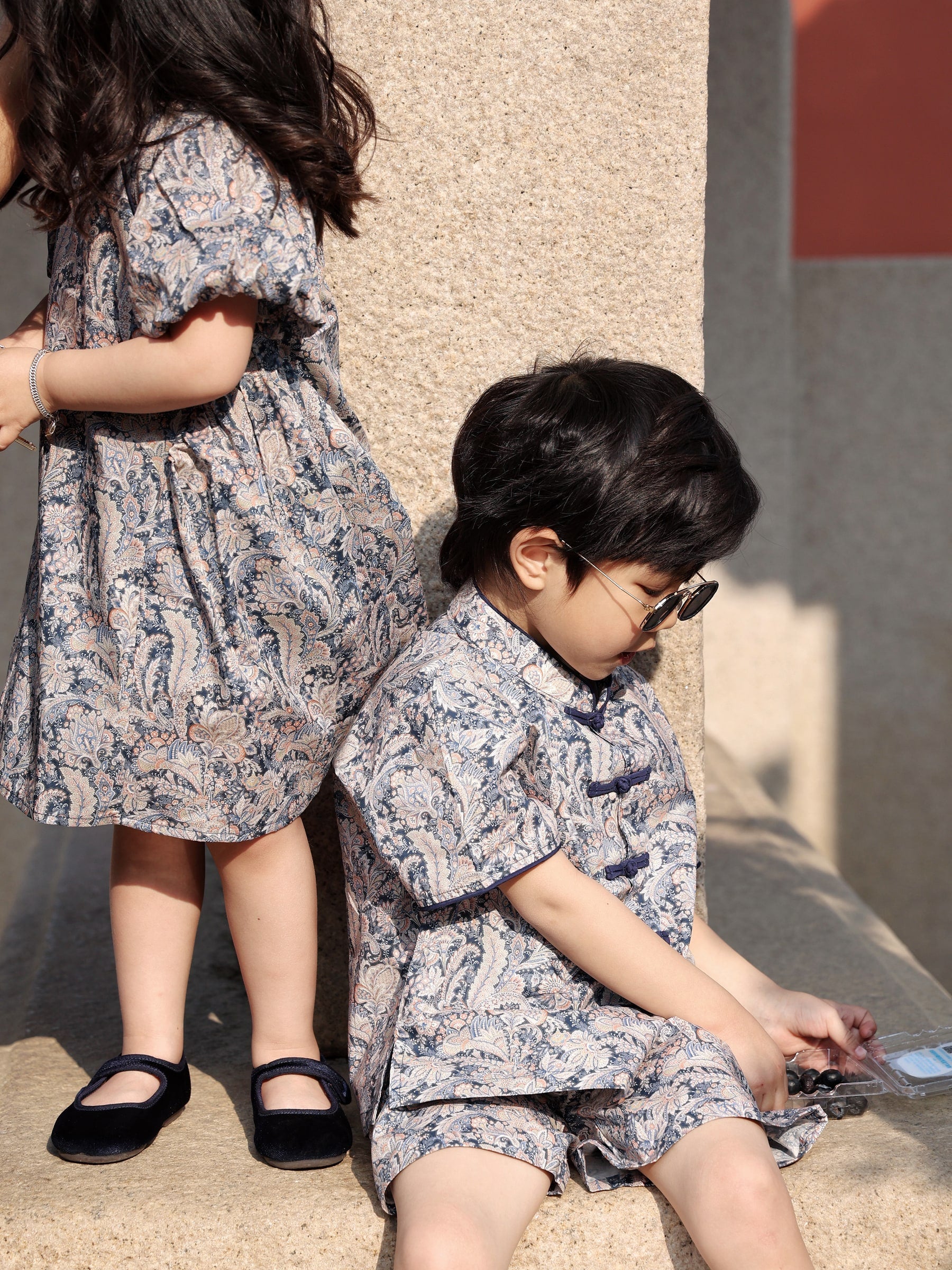 Siblings wearing matching Blue Paisley outfits, close view