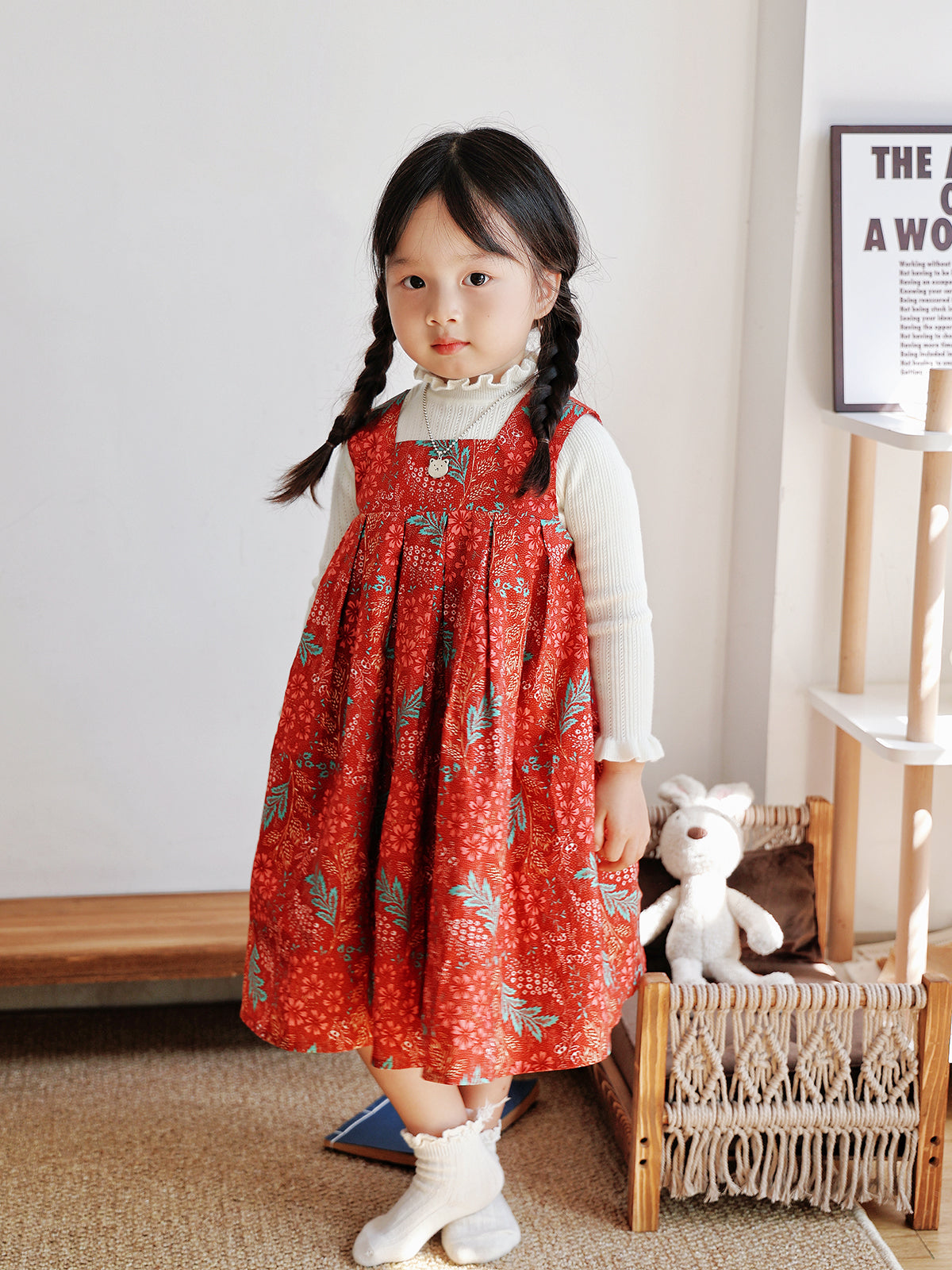 Girl wearing Holiday Bloom red floral dress layered over a white knit