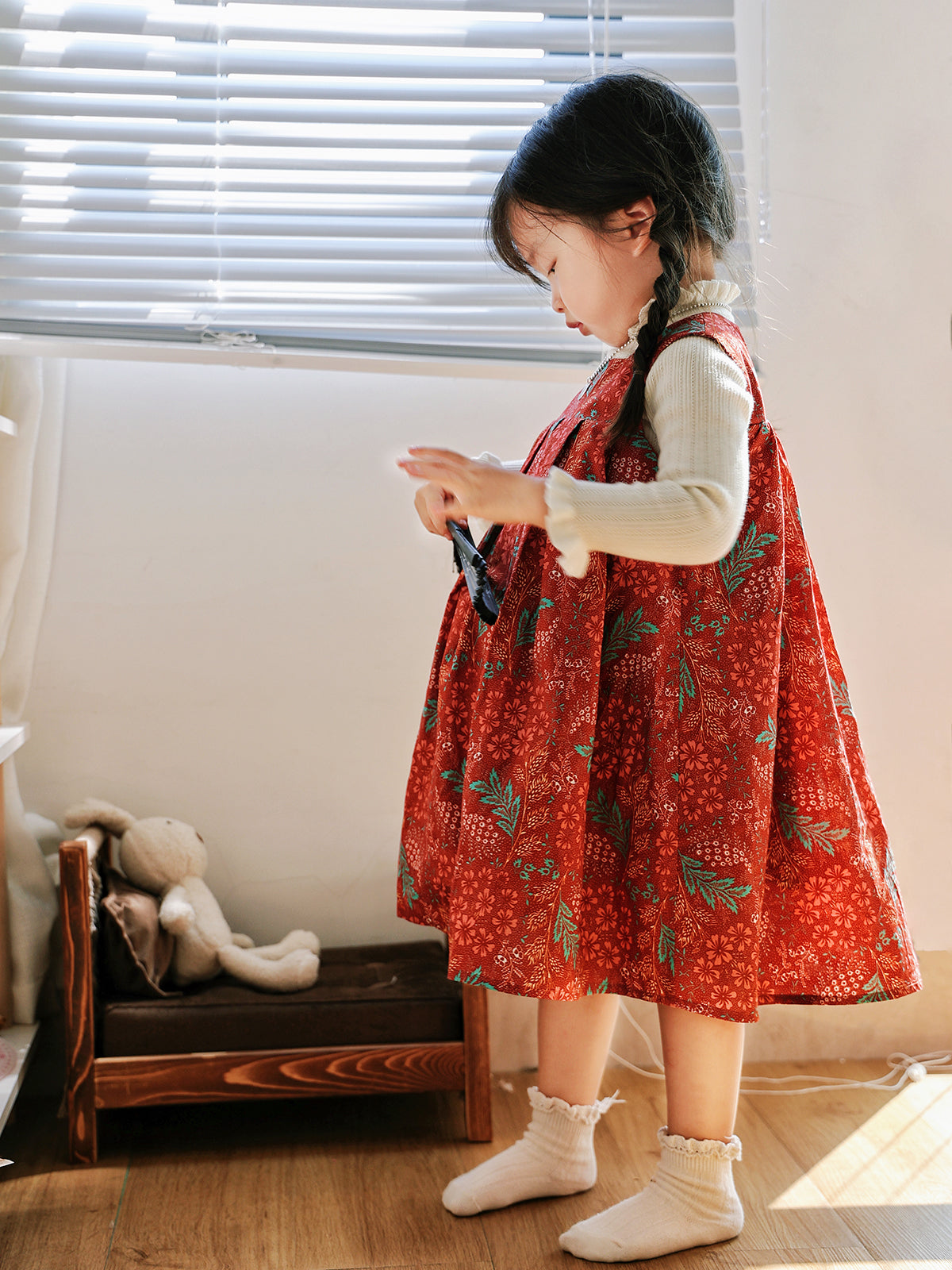 Girl wearing Holiday Bloom red floral dress with white knit layer