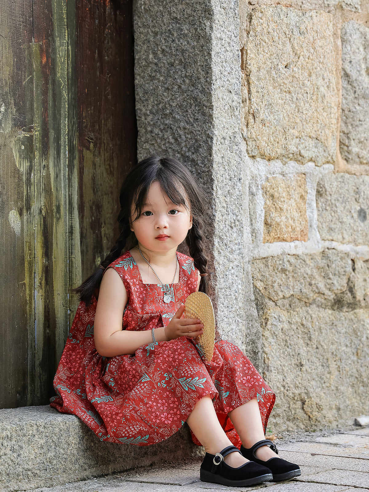 Girl seated in Holiday Bloom red floral sleeveless dress