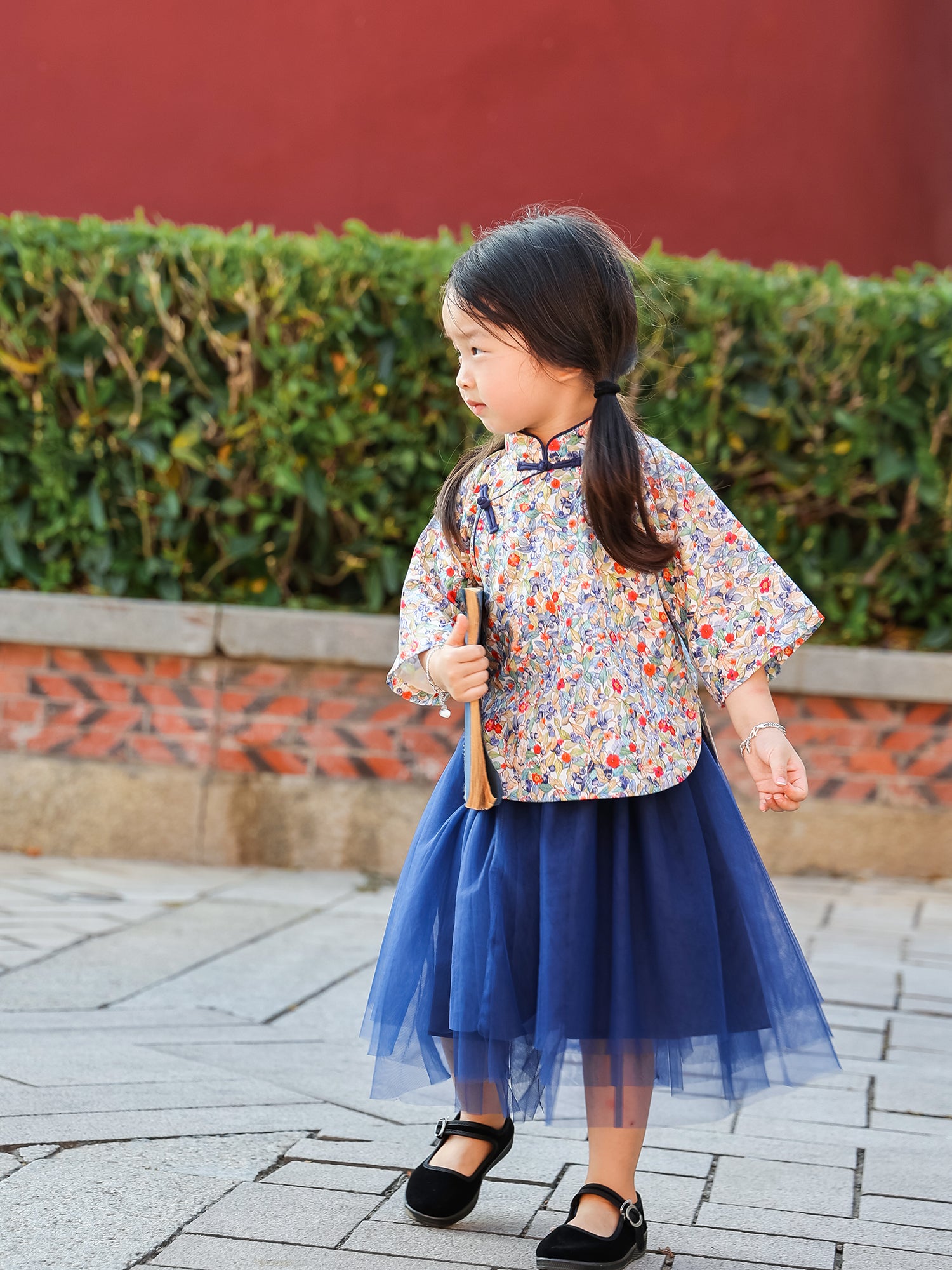 Girl wearing the Indigo Berry floral Mandarin top and navy tulle skirt set outdoors