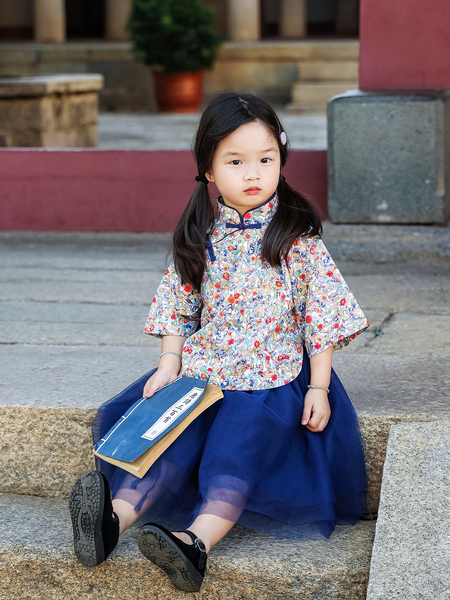 Girl seated in the Indigo Berry floral Mandarin top and navy tulle skirt set