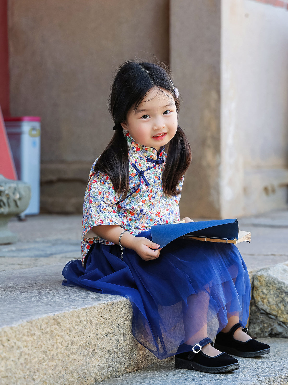 Girl seated in the Indigo Berry floral Mandarin top and navy tulle skirt set
