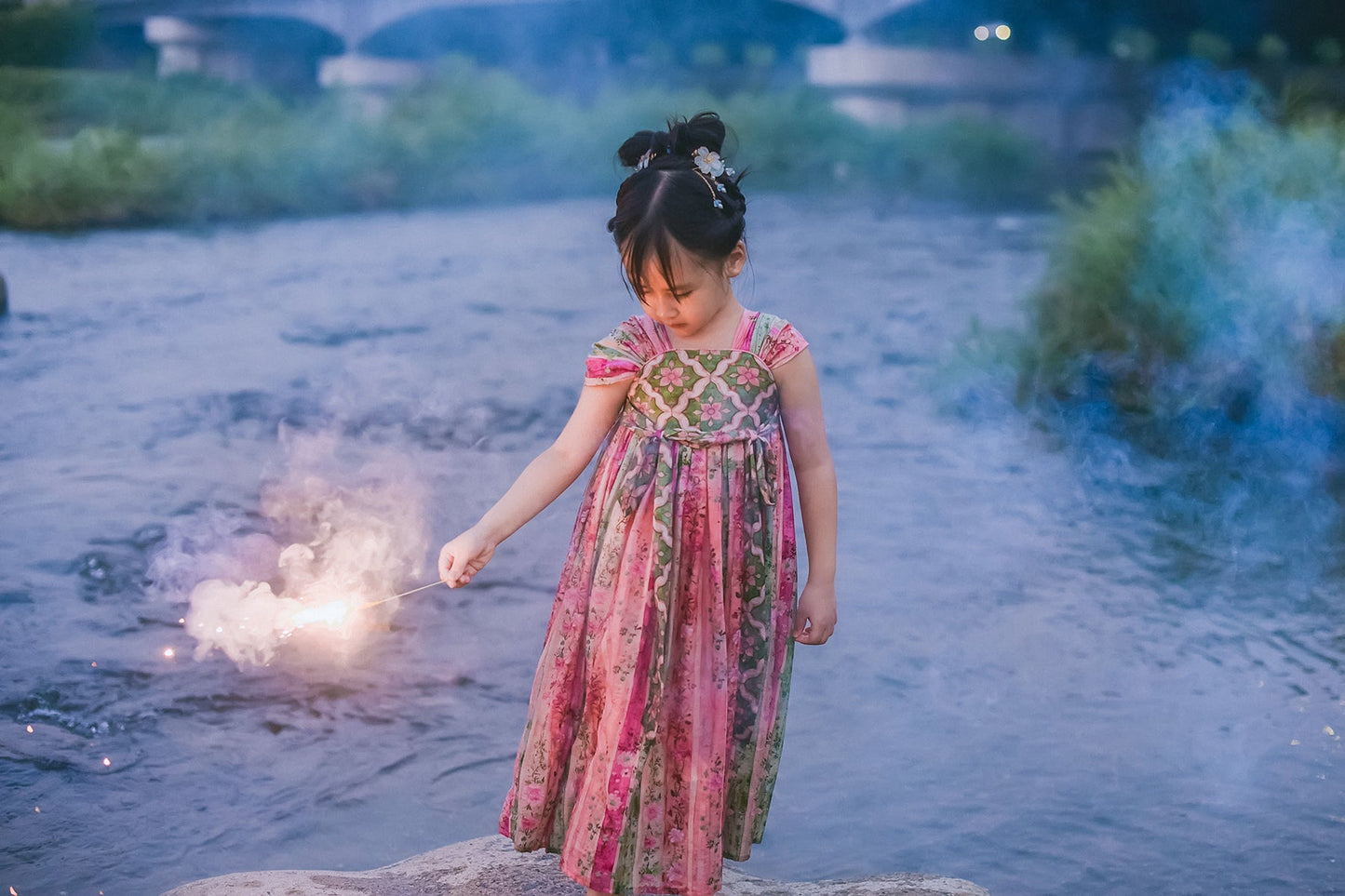 Girl wearing pink and green floral Hanfu-inspired dress by the river