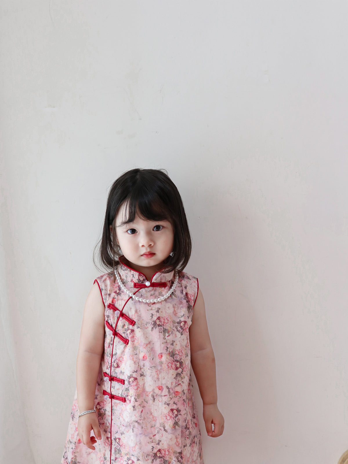 Front view of pink floral sleeveless qipao dress in a warm home setting