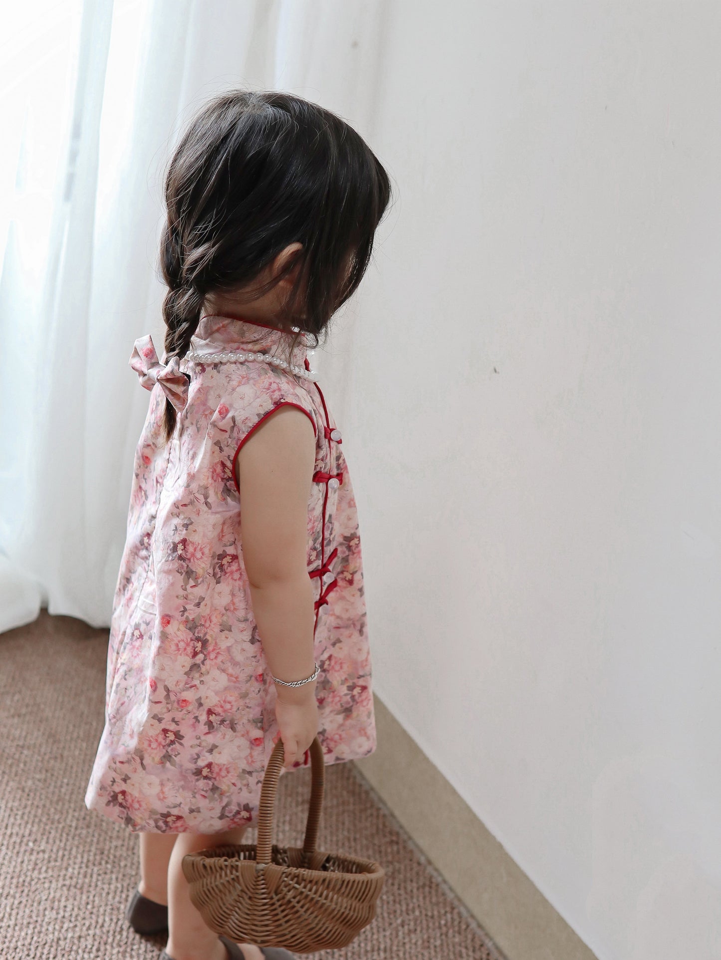 Back and side view of pink floral sleeveless qipao dress in a warm home setting