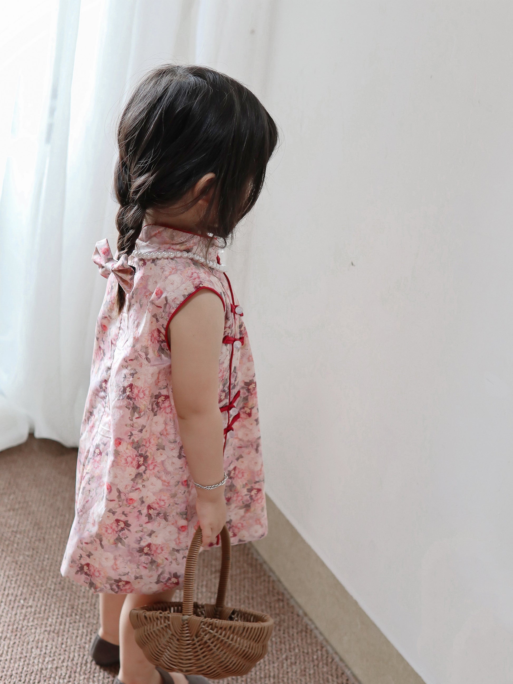 Back and side view of pink floral sleeveless qipao dress in a warm home setting