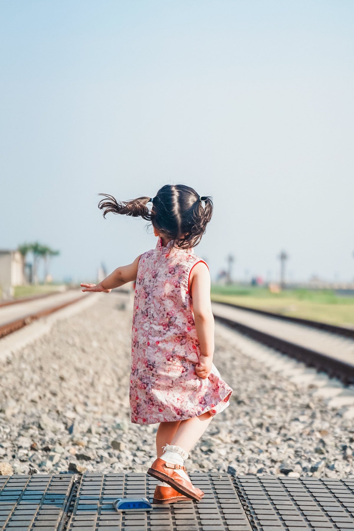 Back view of pink floral sleeveless qipao dress at a railway-themed scenic attraction