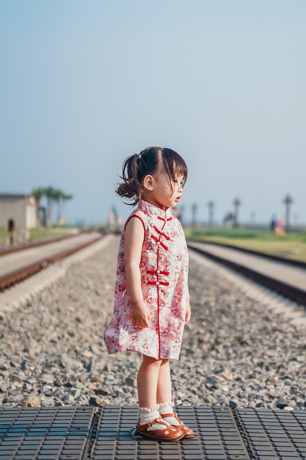 Side view of pink floral sleeveless qipao dress at a railway-themed scenic attraction