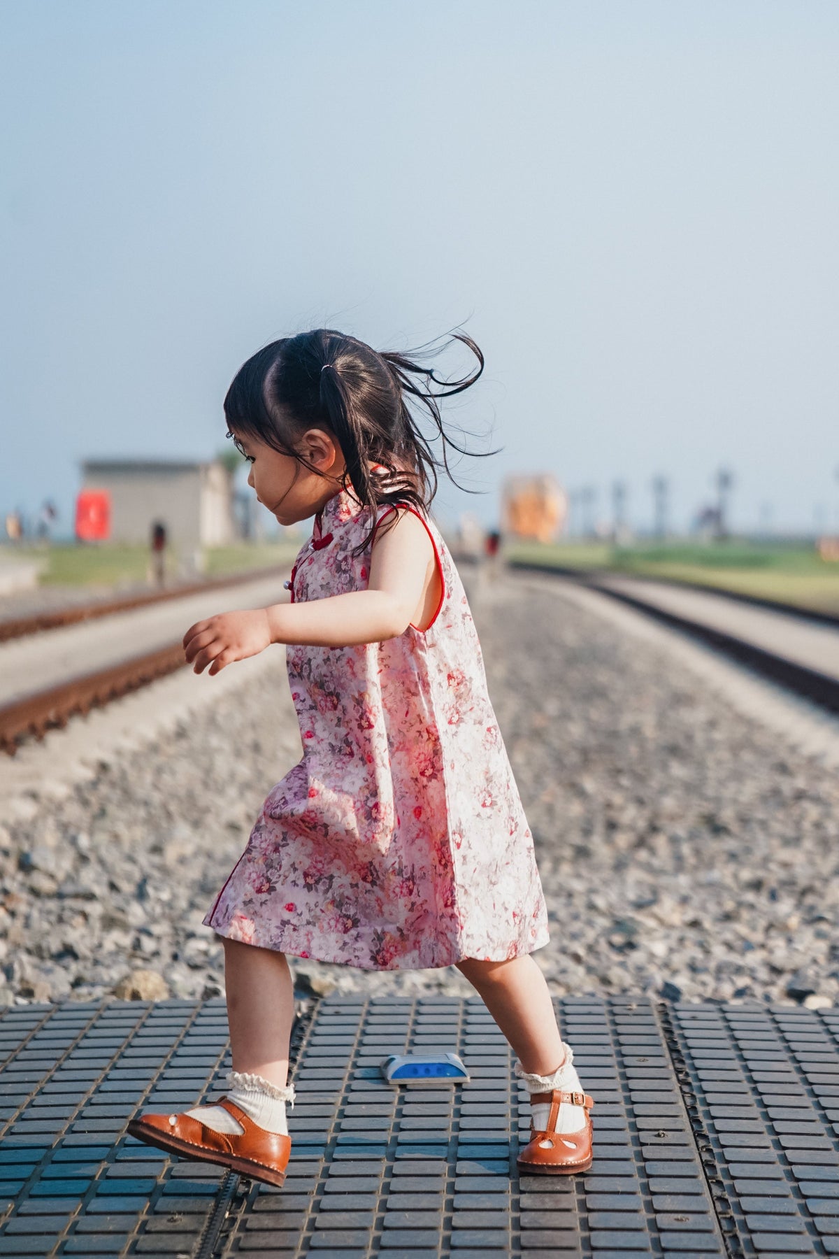 Side movement view of pink floral sleeveless qipao dress at a railway-themed scenic attraction