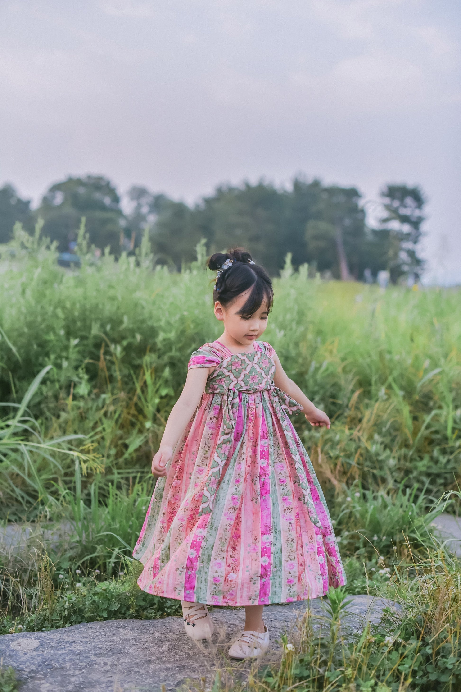 Girl wearing the Rainbow Willow pink and green patchwork Hanfu-inspired dress, full-length view
