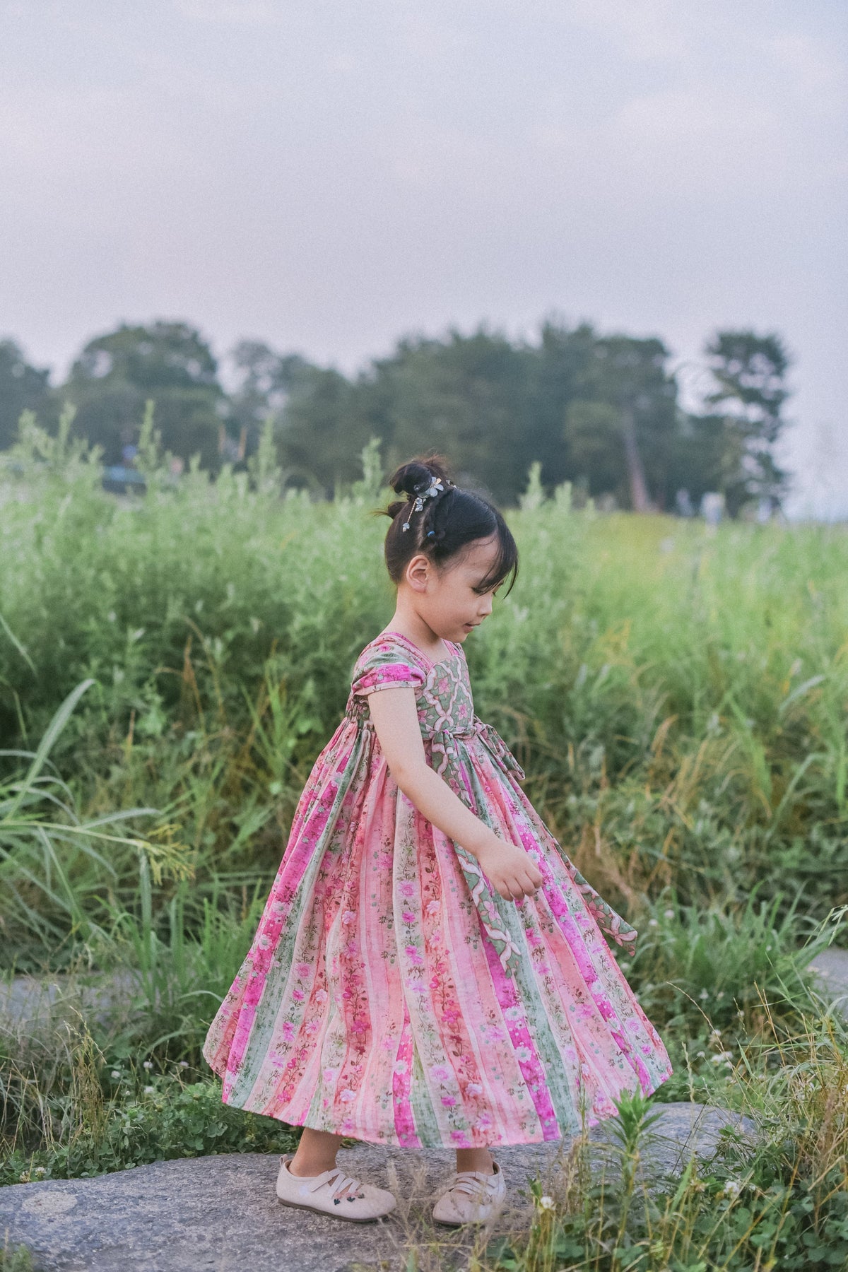 Girl wearing the Rainbow Willow pink and green celebration dress outdoors